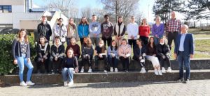 Eine 23köpfige Schülergruppe der Heinrich-Böll-Schule stehen mit Französischlehrerin Christina Walder (l.) und Oberstudienrat Sven Spottka (2.v.r.). Schulleiter Alexander Hauptmann (r.) zusammen auf dem Schulgelände. Anlass ist das Erlangen des französischen Sprachdiploms.