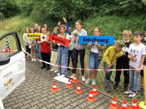 Schüler/innen der Klasse 5/5 zeigen auf Schildern die Formel für den Anhalteweg