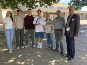 Bild von Bernd Schmitt, der Kunstlehrerin Samire Burniki, Schulleiter Alexander Hauptmann und Schülerinnen und Schülern bei der Spendenübergabe.