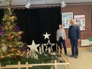 Bild von Herrn Hauptmann und Schulpfarrerin Barbara Holzapfel-Hesselmann neben der neuen Krippe und Weihnachtsbaum.