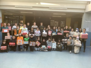 Schüler/innen stehen mit Geschenken in der Hand für Kinder in Not im Foyer der Schule