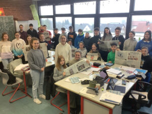Das Foto zeigt Referendar Eike Brunnengräber und die Schülerinnen und Schüler seines A-Kurses mit Zeitungen