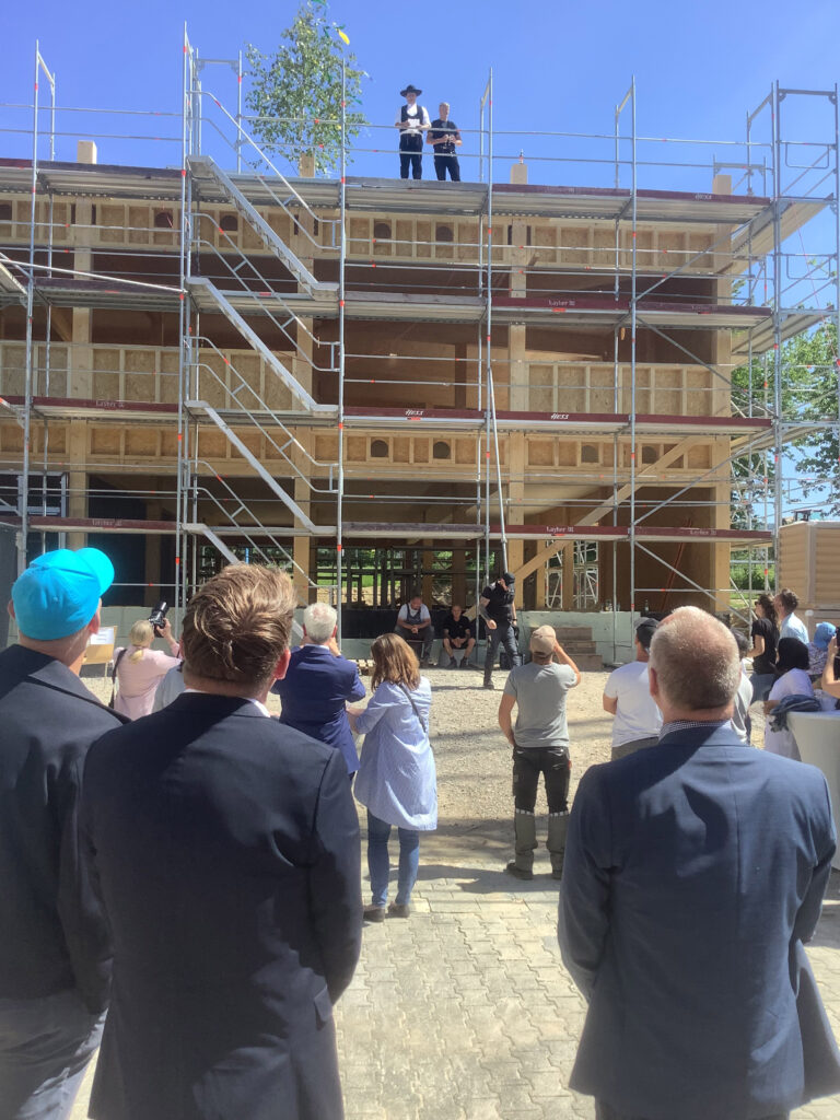 Menschen stehen vor dem Neubau und der Richtspruch wird verkündet