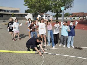 Schüler jubeln während Feuerwehrschläuche auf dem Schulhof angekuppelt werden