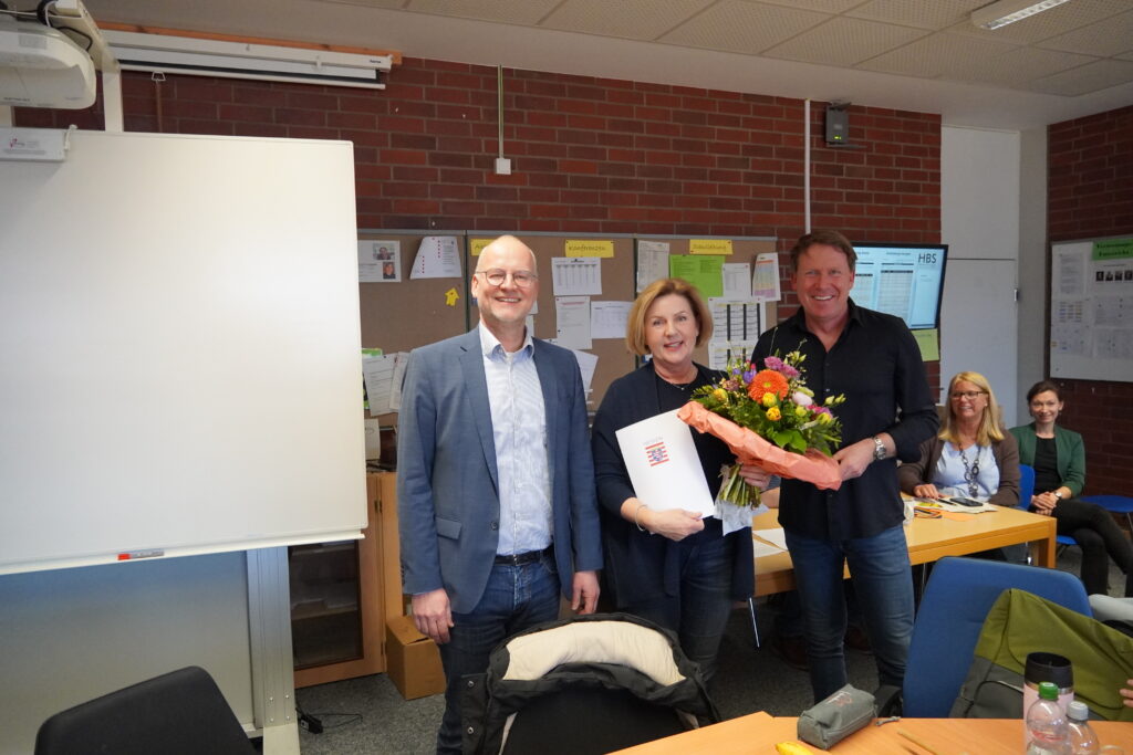 Herr Hauptmann (links) und Herr Oberele (rechts) verabschieden Kerstin Schmitt (Mitte) mit einem Blumenstrauß in den Ruhestand