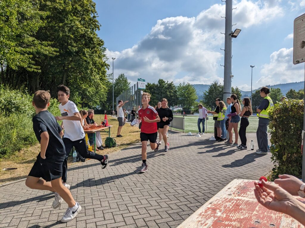 Das Bild zeigt Schüler/innen beim Rennen um den Sportplatz