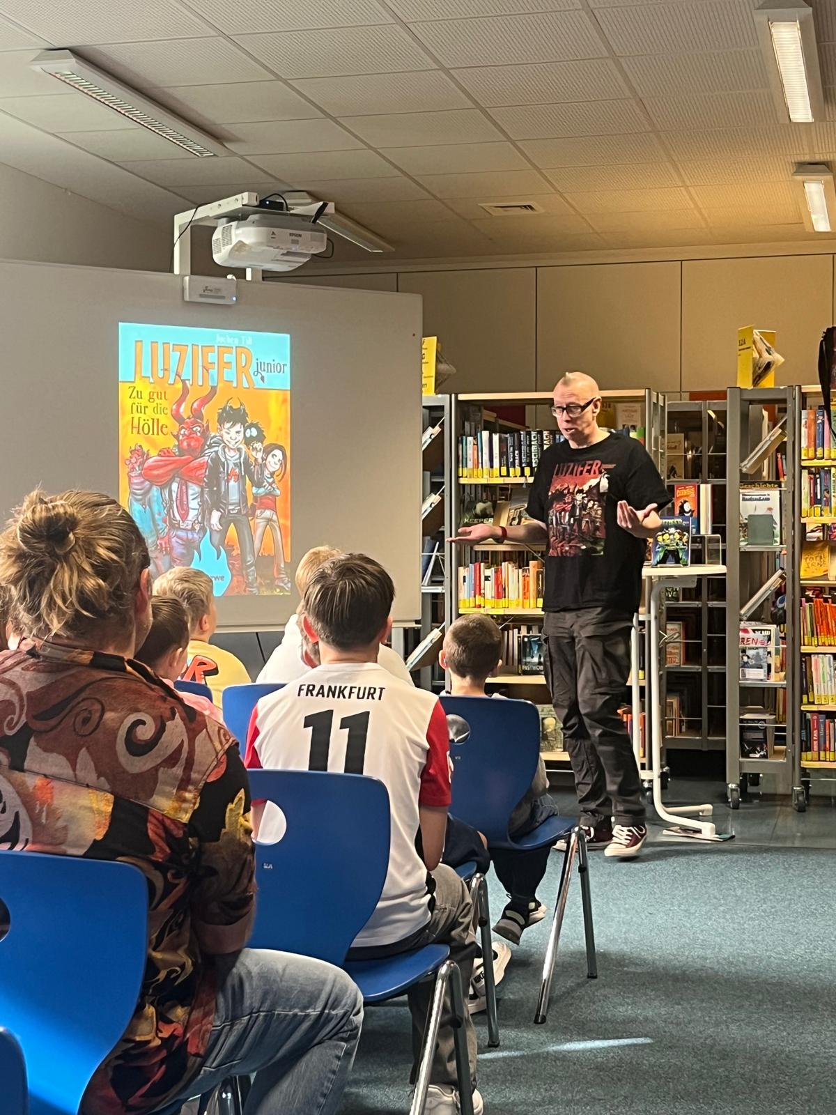 Autor Jochen Till steht in der Mediothek vor Schüler/innen