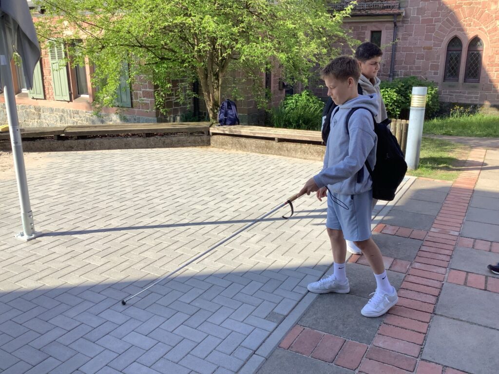 Das Bild zeigt einen Schüler mit einem Blindenstock