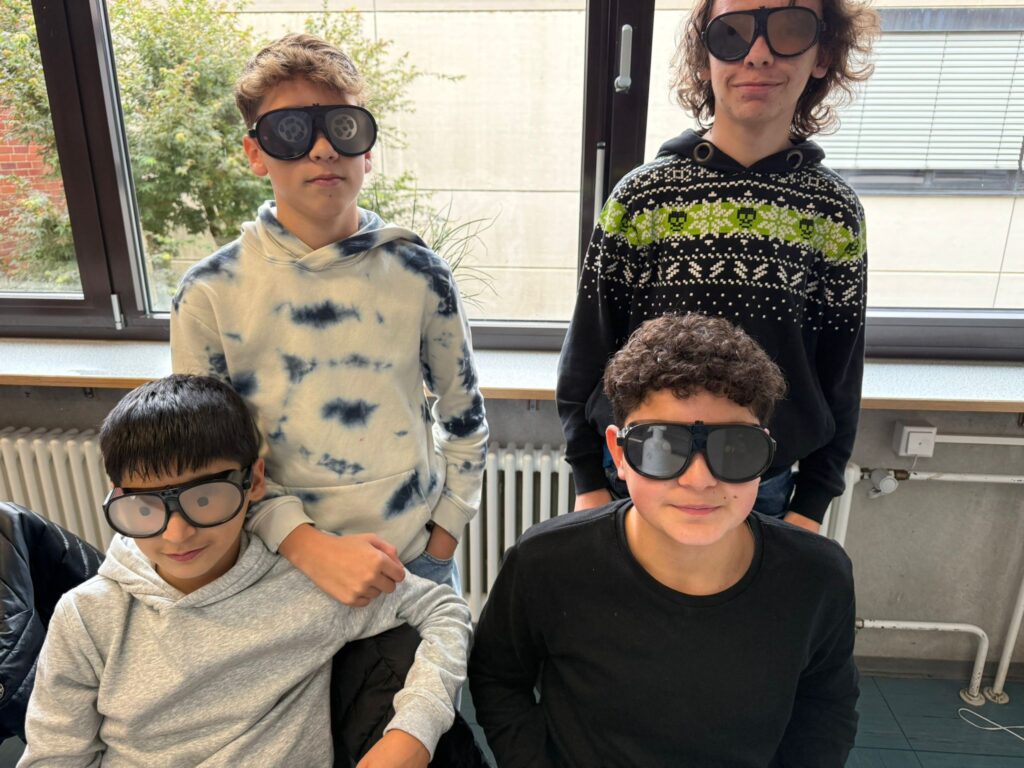 Das Bild zeigt 4 Schüler, die verschiedene Brillen tragen, die die Wahrnehmung beeinflussen