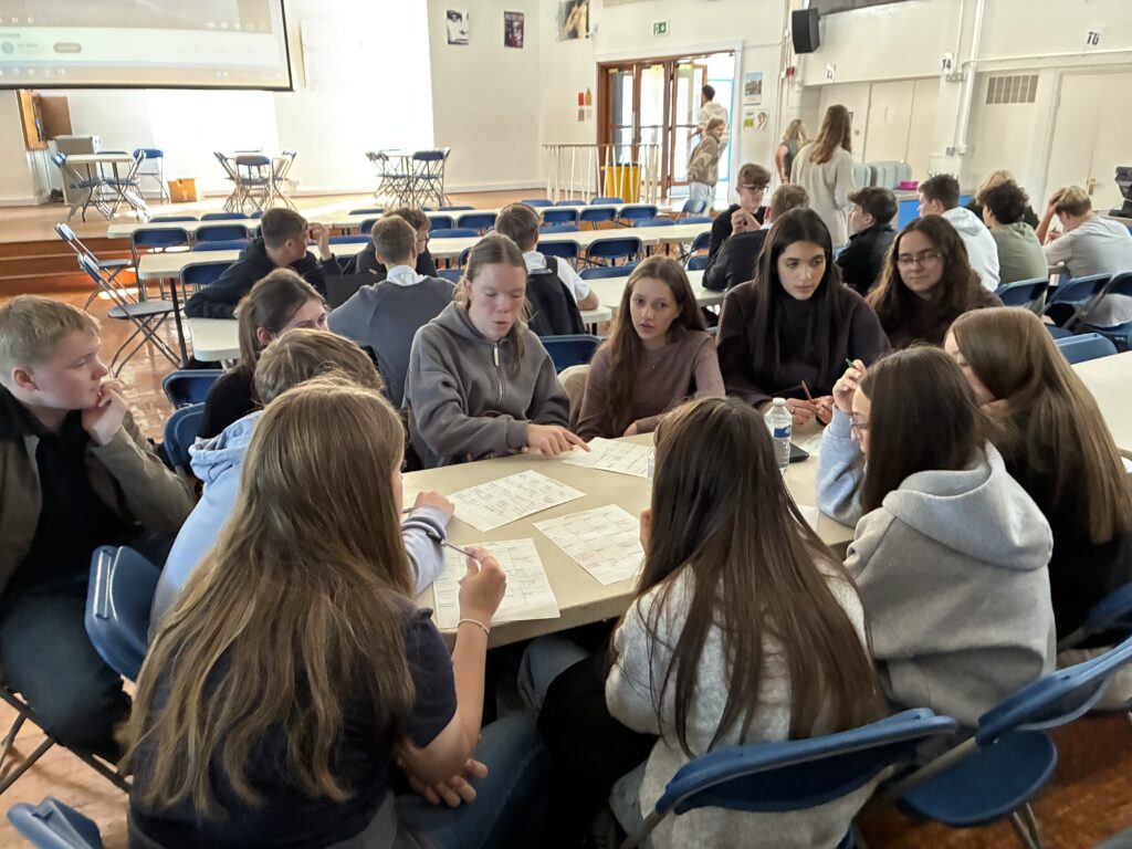 Schüler/innen sitzen zusammen an einem Tisch in einer englischen Schule