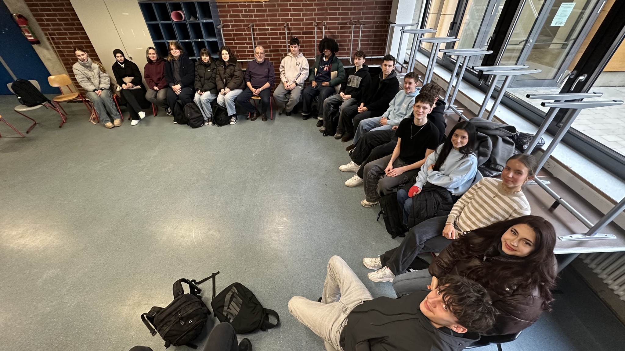 Schüler/innen sitzen im Stuhlkreis und hören dem Referenten zu