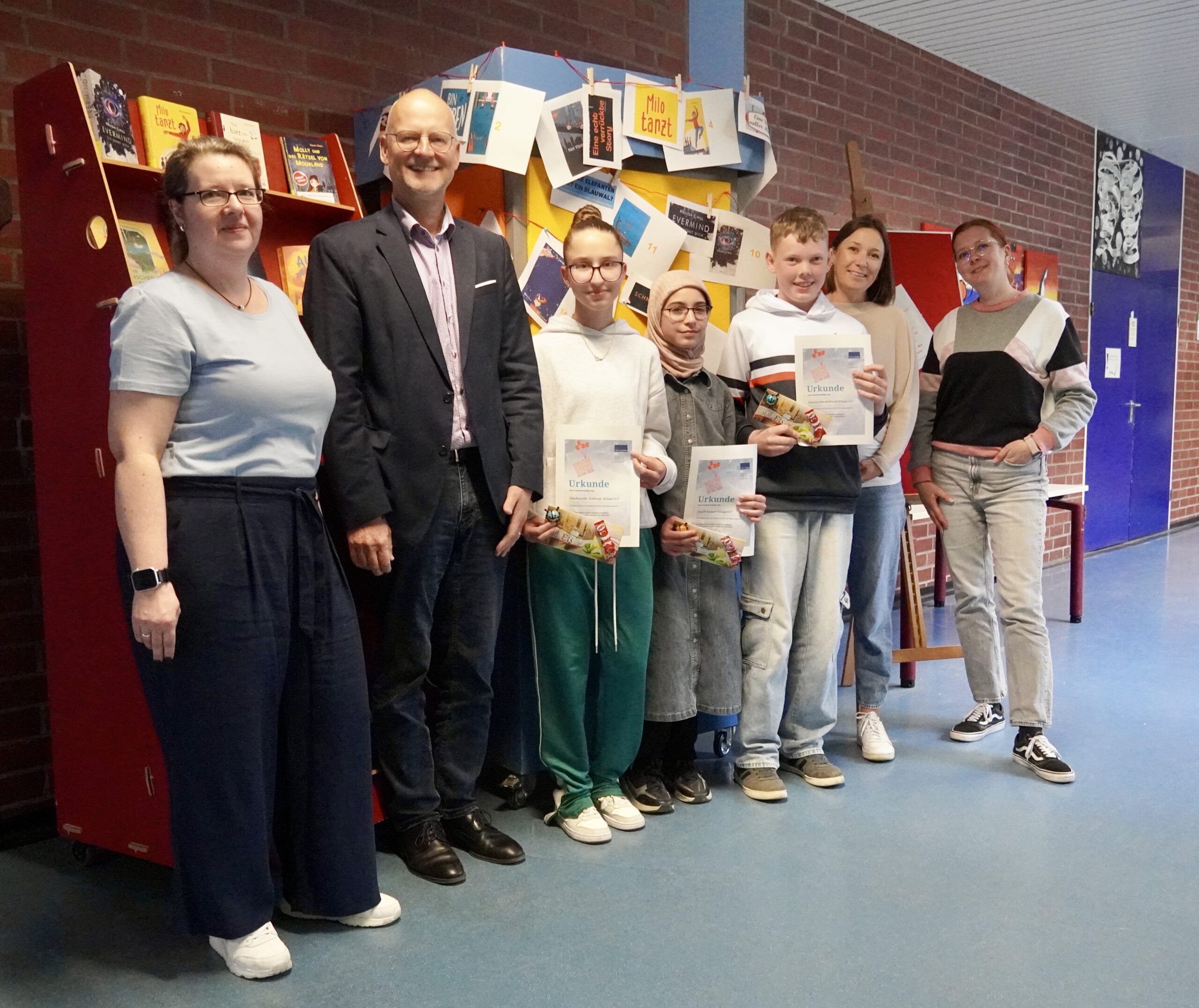Beteiligte der Aktion Welttag des Buches stehen in einer Reihe an der Wand gegenüber der Mediothek